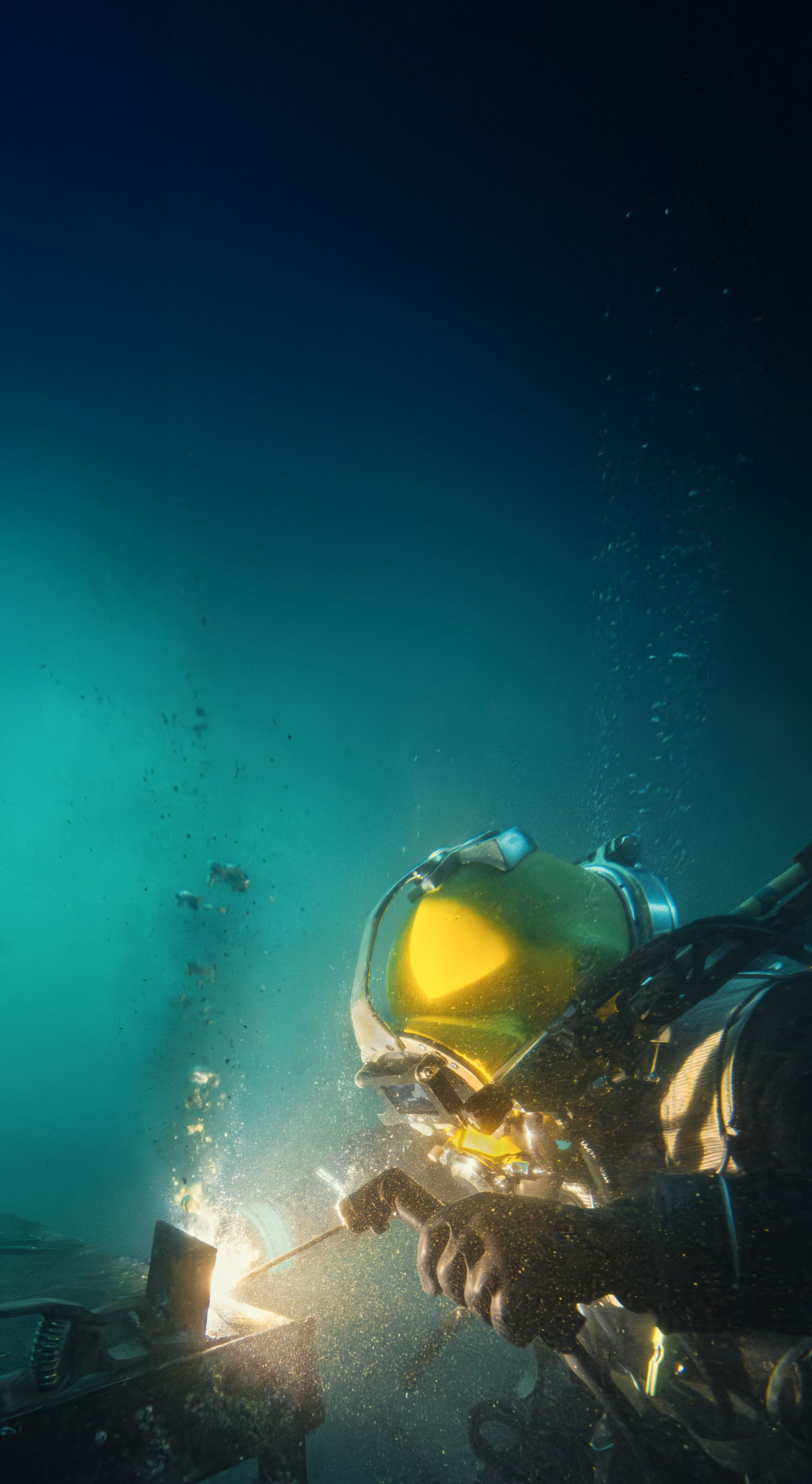 Industrial diver welding underwater with yellow helmet