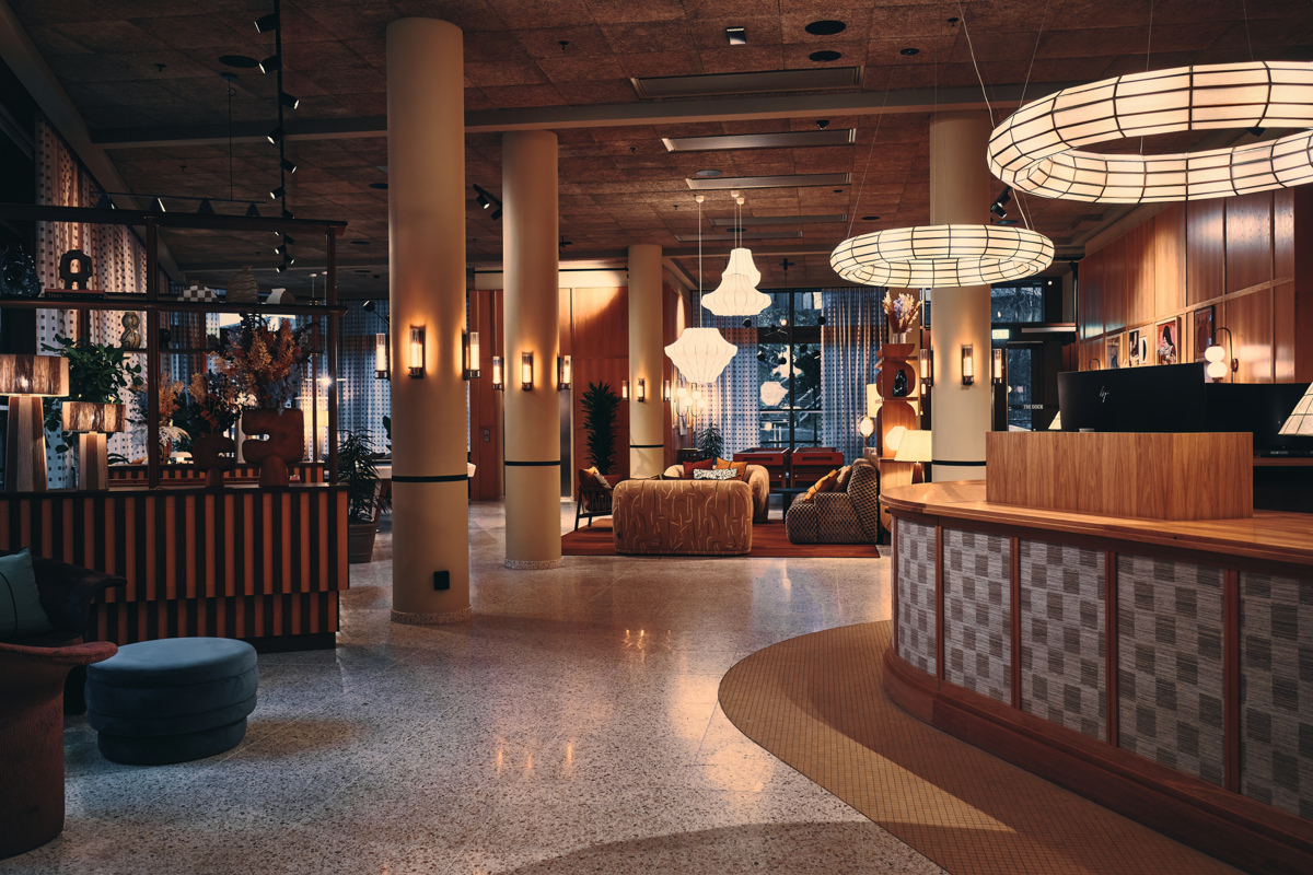 Elegant hotellobby med träpaneler, mjuk belysning, bekväma soffor och stora, rundade takkronor.