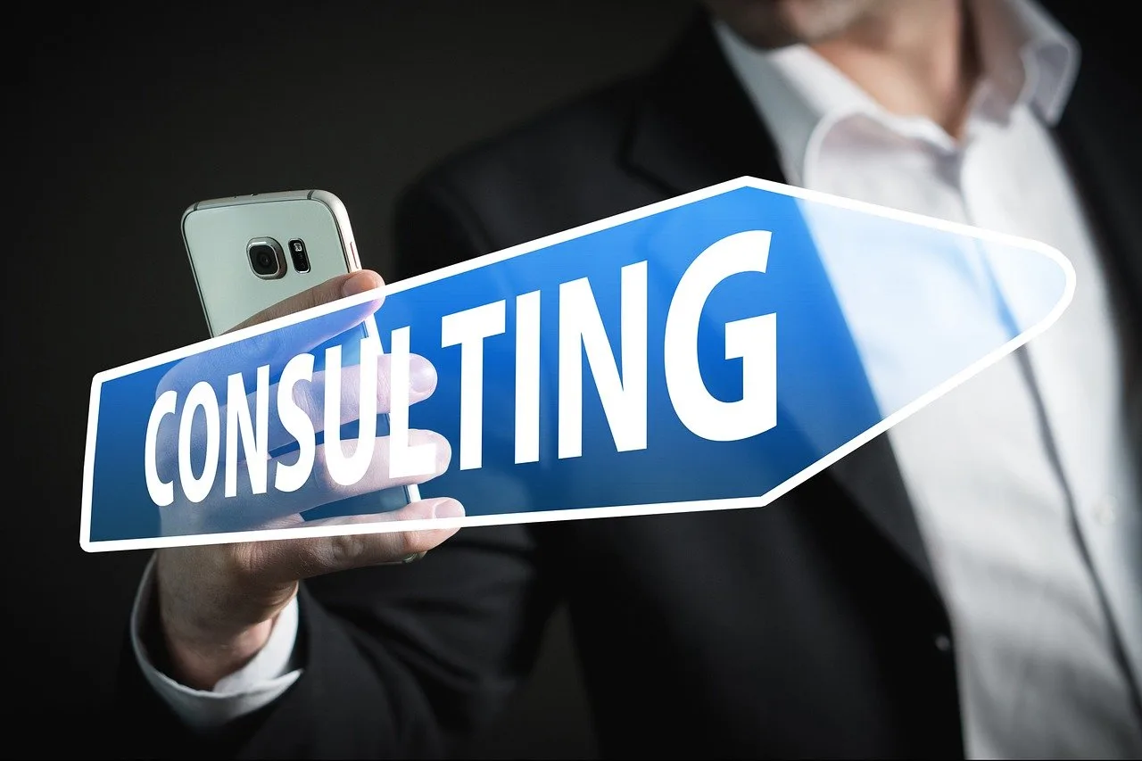 Businessman holding a smartphone with a 'CONSULTING' sign, symbolizing professional consulting services and mobile business solutions.