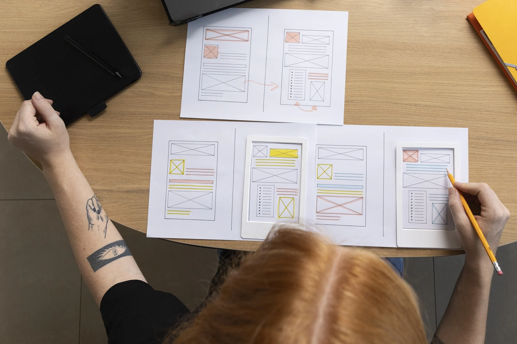 Designer sketching mobile wireframes as part of the UX Design Process with user interface layouts on paper.