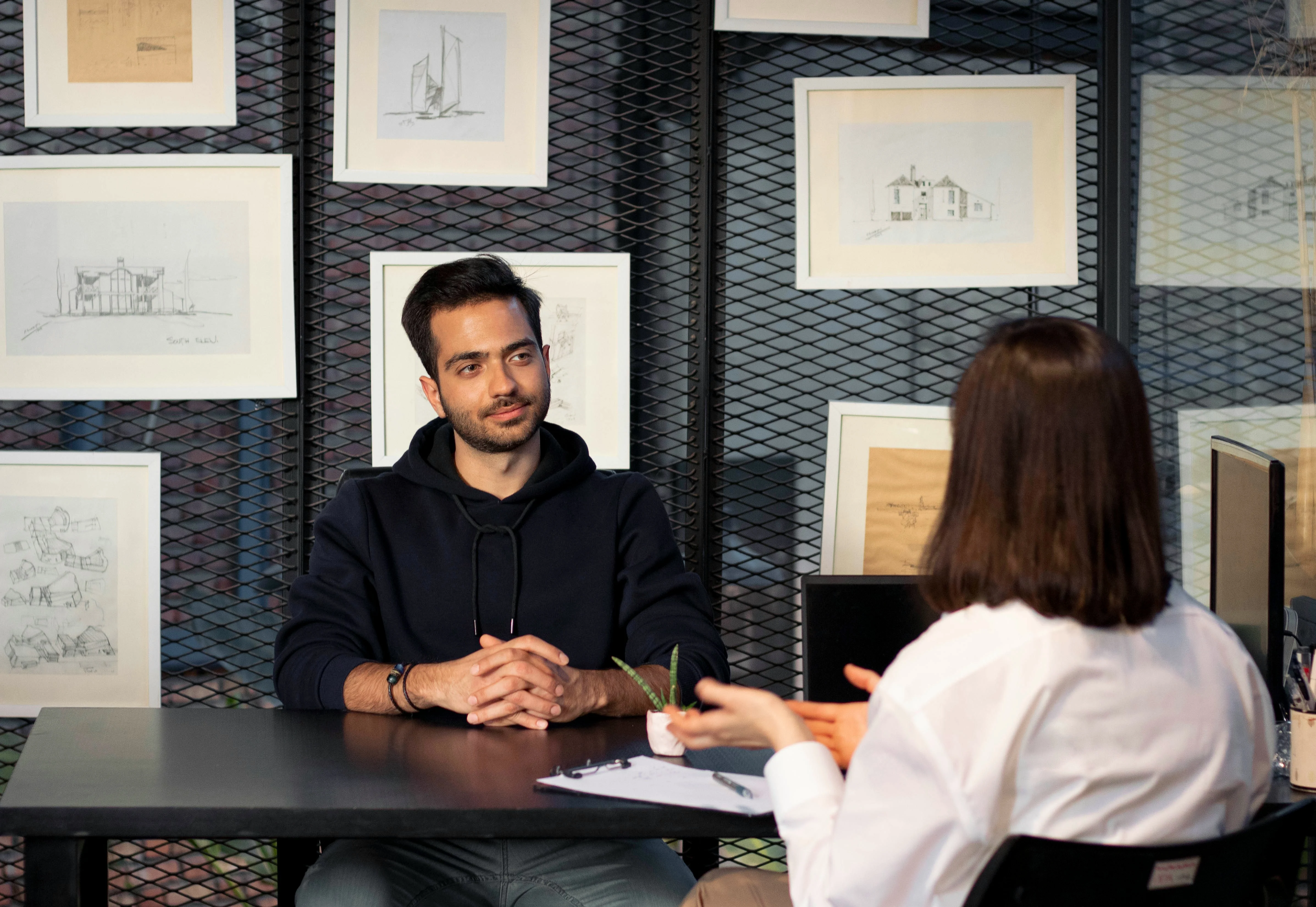 Man and woman in a professional user interview setting with architectural sketches in background.