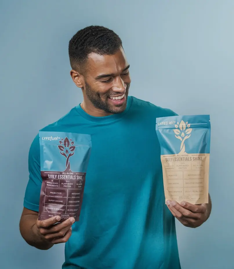 Man holding LYFEfuel Daily Essentials packets, plant-based supplement
