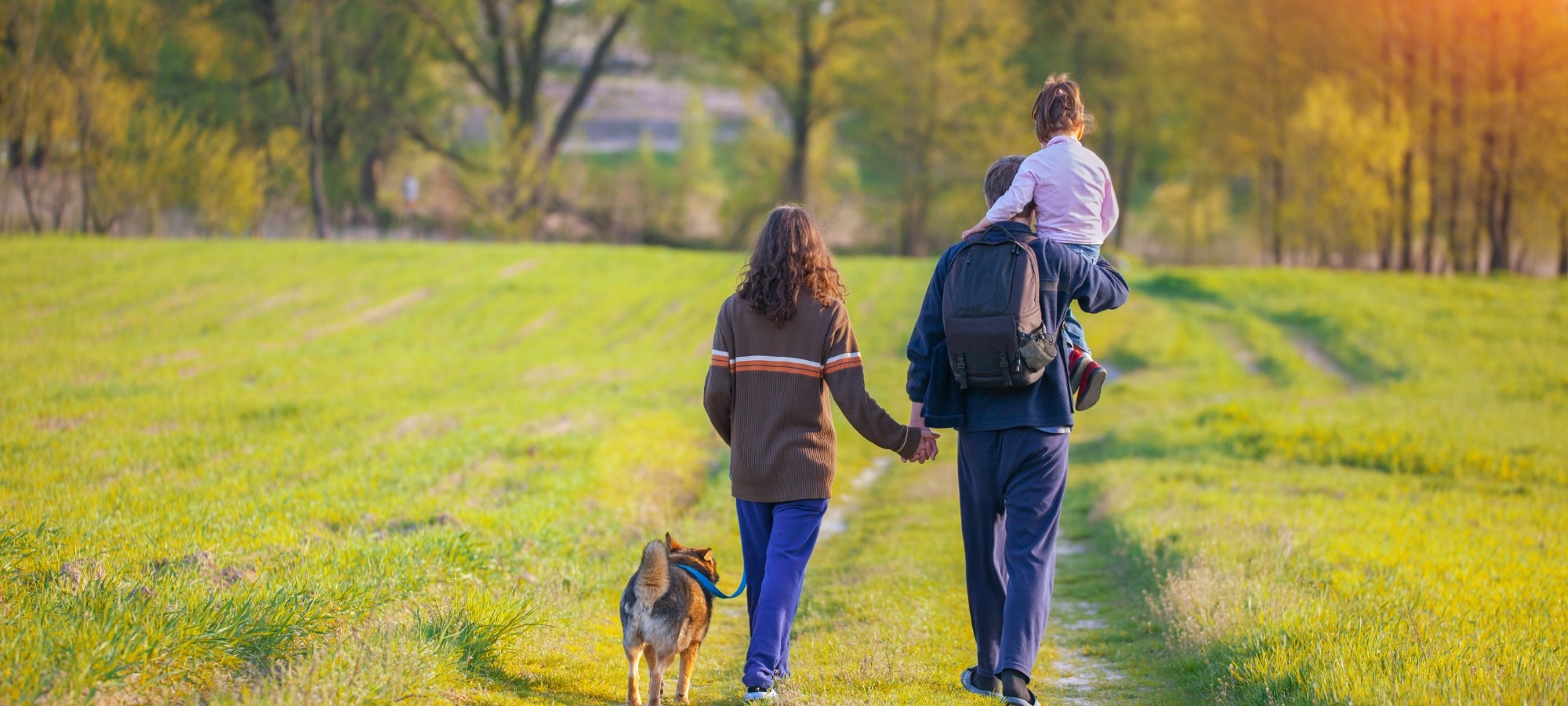 A family walking across a field with a dog