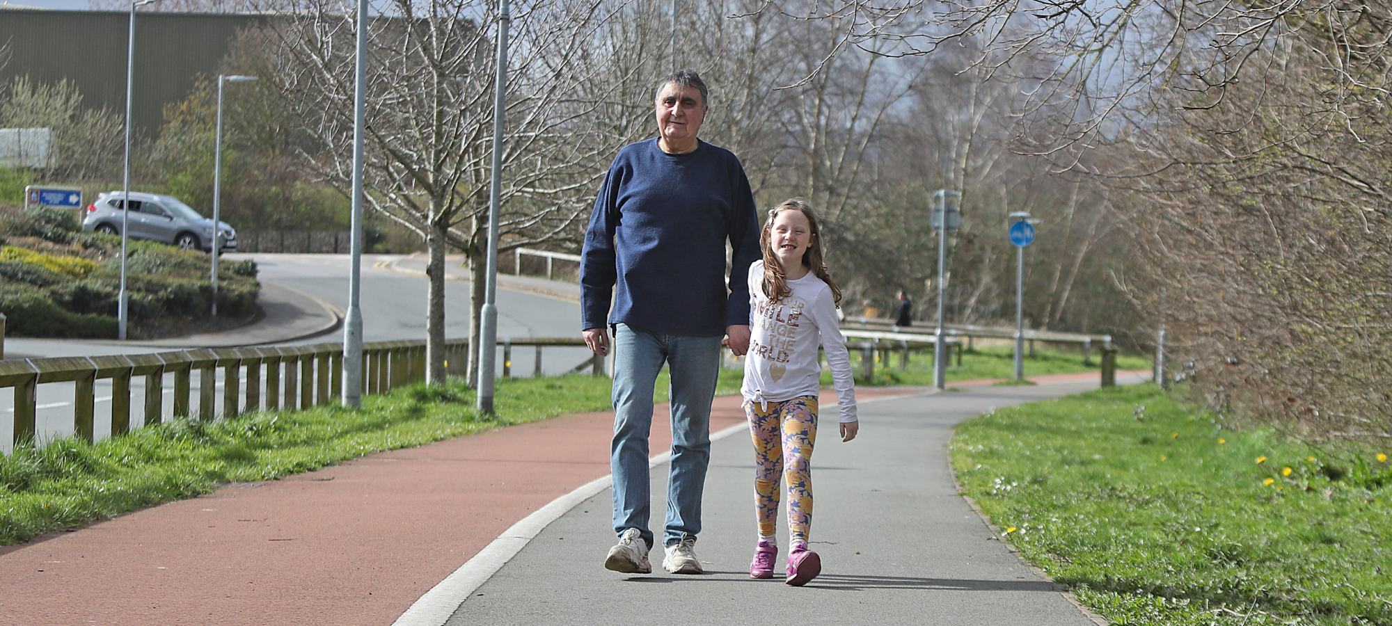 Man and child walking along footpath.