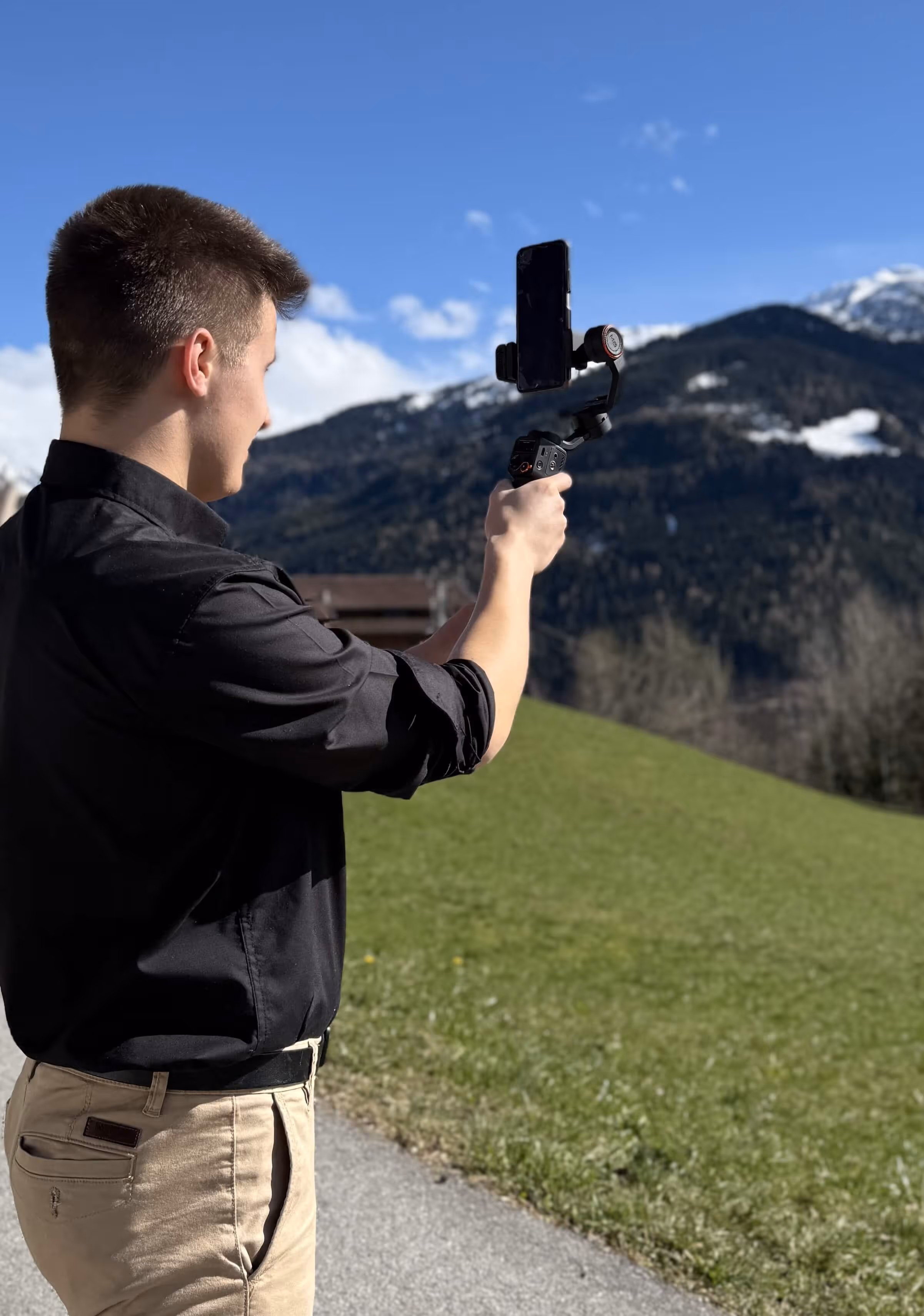 A camera man filming in the mountains with a gimbel and a smartphone.