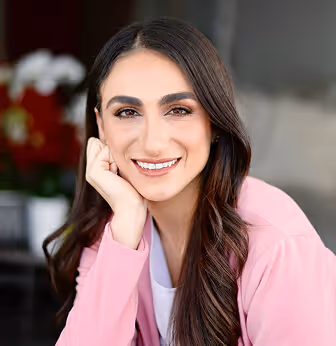 Retrato de Stephanie Essenfeld, psicoterapeuta, sonriendo y apoyando su cabeza en su mano.