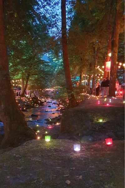 Kleiner Fluss, der mit bunten Teelichtern gesäumt wird