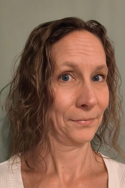 Eine Frau mit Lockenkopf lächelt in die Kamera