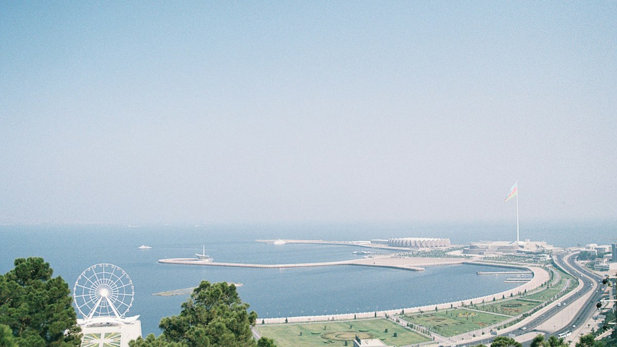 Baku Boulevard and the Caspian Sea seen from above, with the ferris wheel in the foreground and the national flag square on the headland