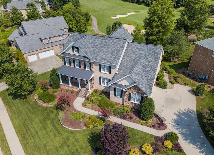 An aerial view of a home with a golf course in the background.