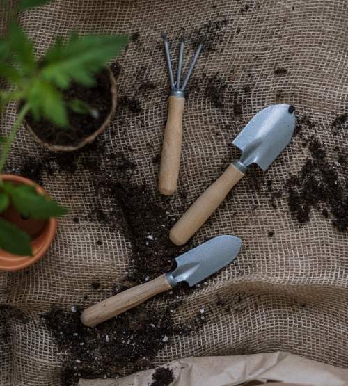 Gardening utensils laying on top of a sack of dirt.