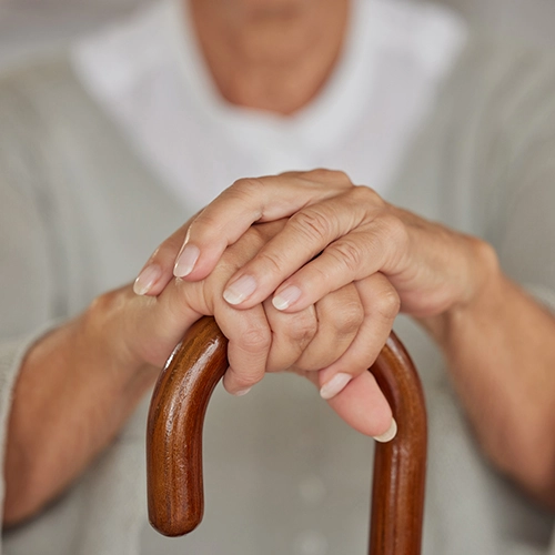 Hands of an older woman holding a walking aid for osteoarthritis patients.