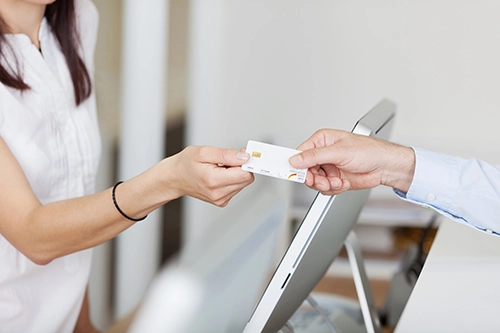 Someone hands a credit card to someone else over a counter.