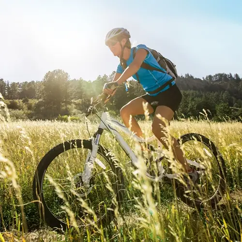 The sun shines as a man recovered from sports injuries rides his bicycle on a country road.