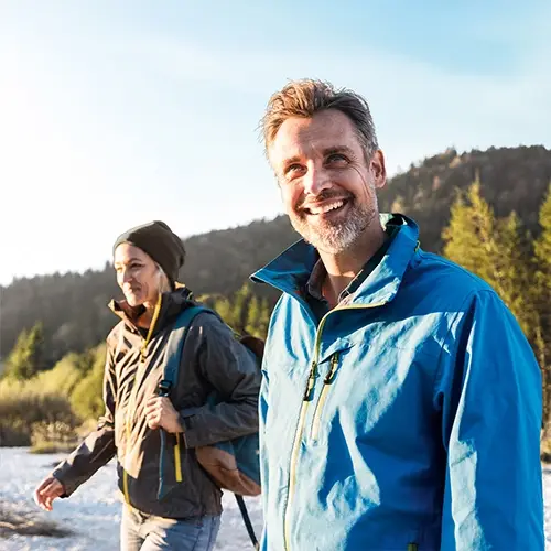 A couple is smiling as they go on a nature walk pain-free despite arthritis.