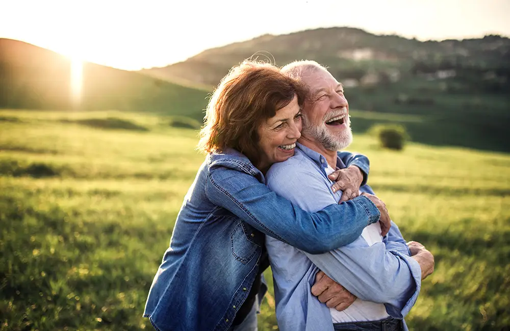 Side-on view of a couple hugging surrounded by nature in spring at sunrise.