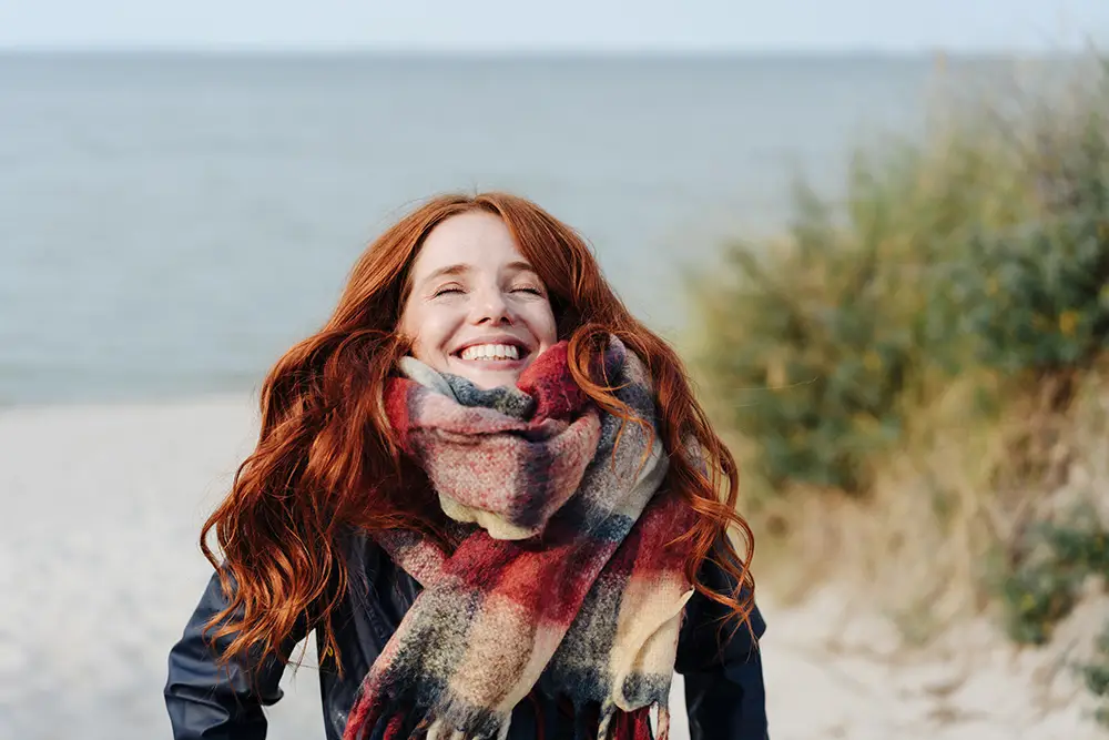 Happy pale woman with red hair on the beach.