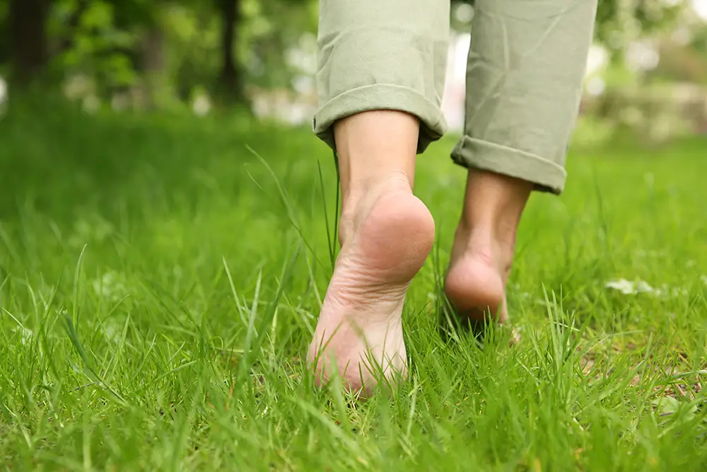 A woman walks barefoot across a fresh meadow.