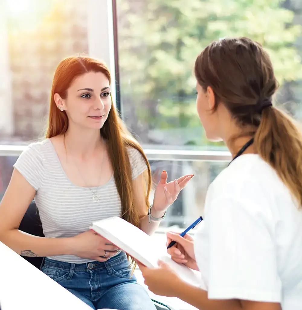 A female patient has a consultation with a doctor in a bright, friendly room.