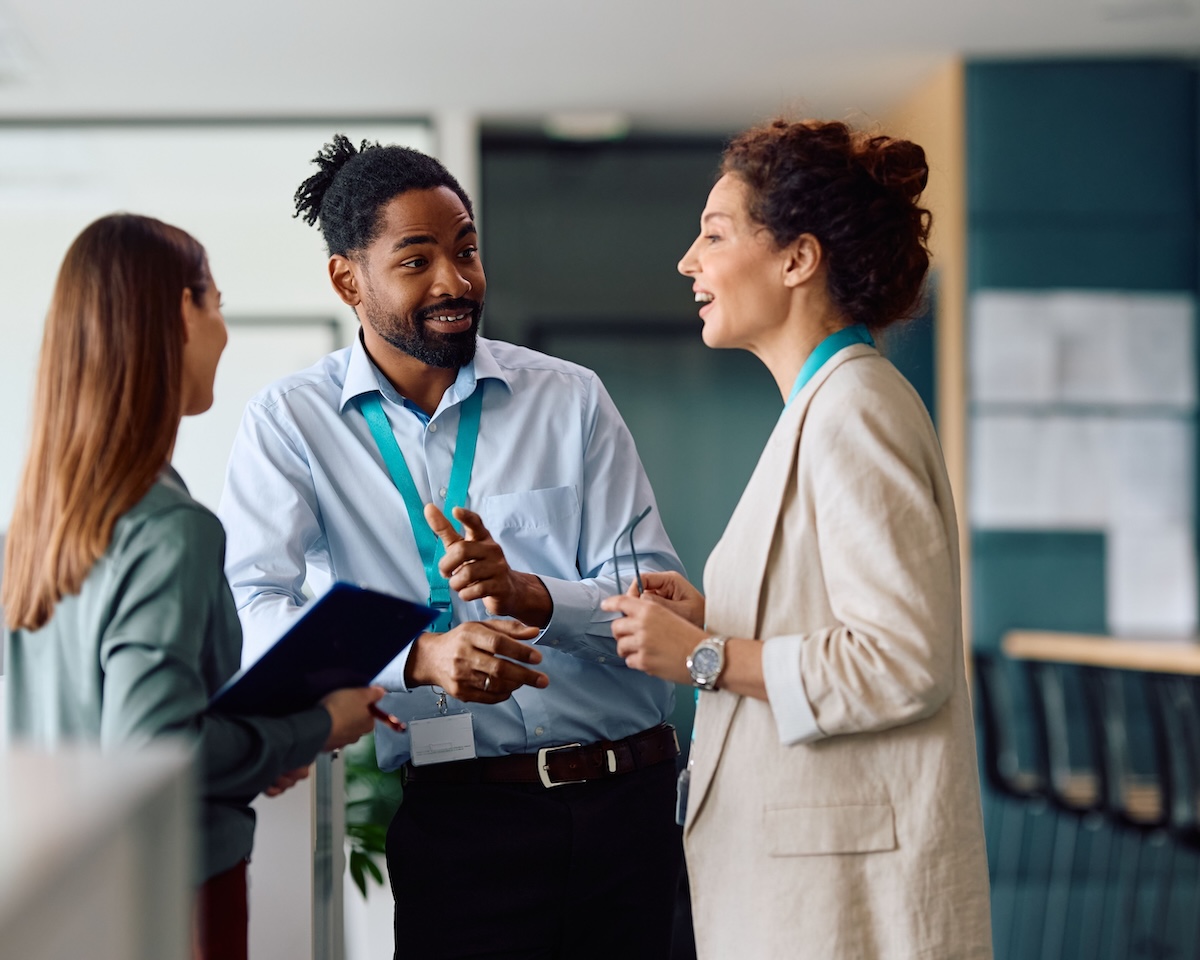 Trois collègues discutent et échangent de manière informelle dans un environnement de travail, illustrant la collaboration, l’écoute et les interactions professionnelles au sein d’une équipe.