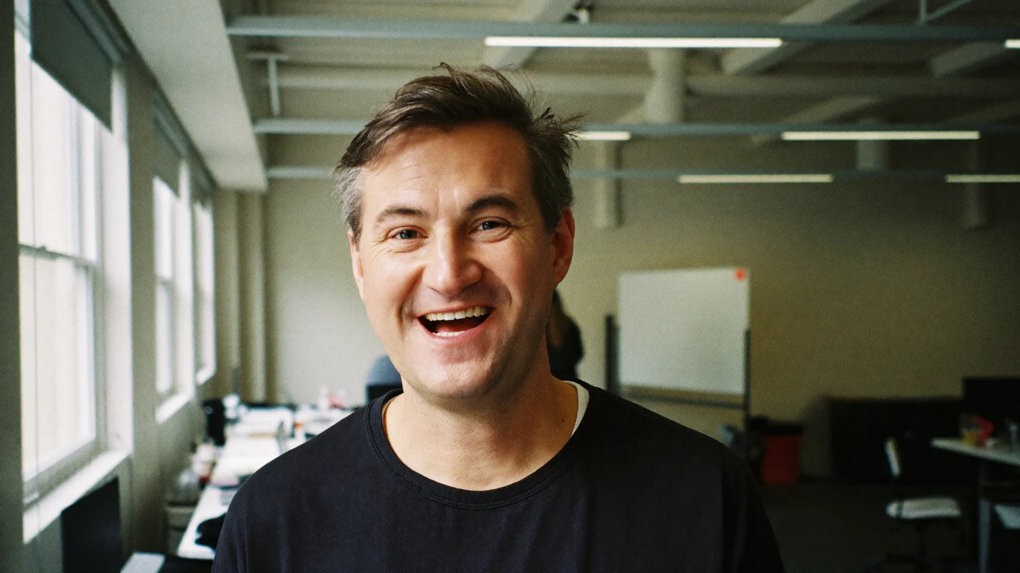 A marketing director smiling mid-conversation in an open-plan office