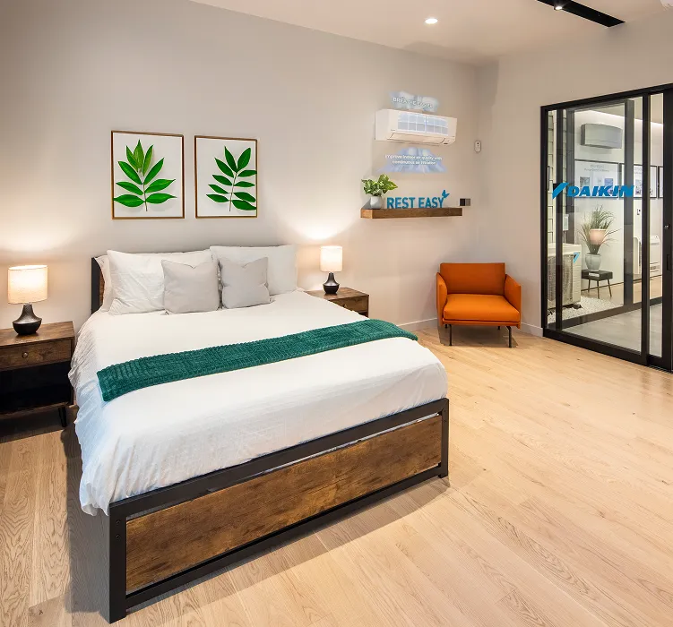 Modern bedroom with white bed, orange chair, leaf art, and glass door
