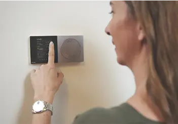 Person adjusting wall-mounted digital thermostat or control panel
