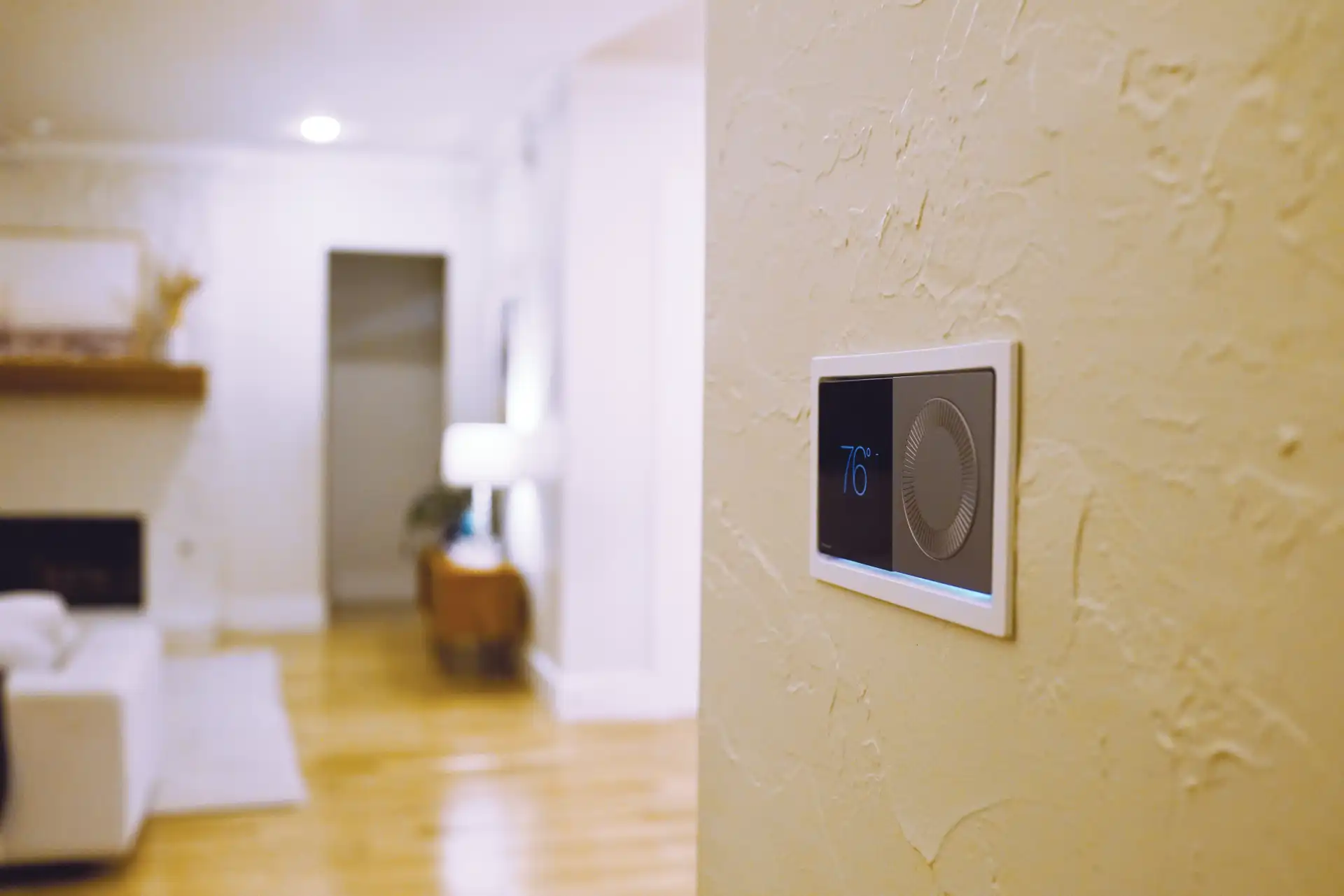 Digital thermostat on textured wall showing 76 degrees