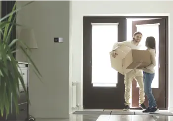 Couple moving boxes into new home, standing in doorway together