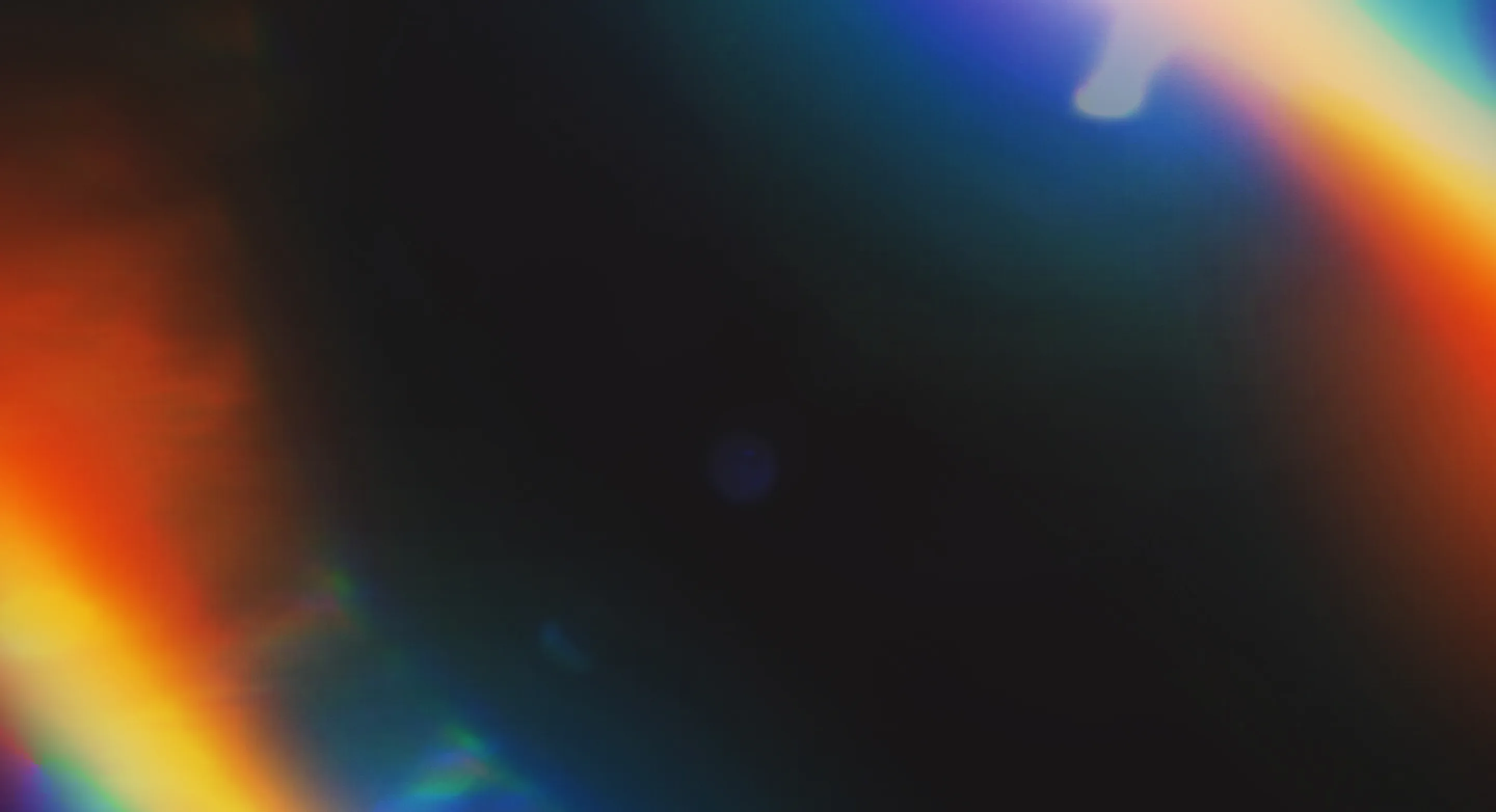 Dark background crossed by warm prismatic light leaks