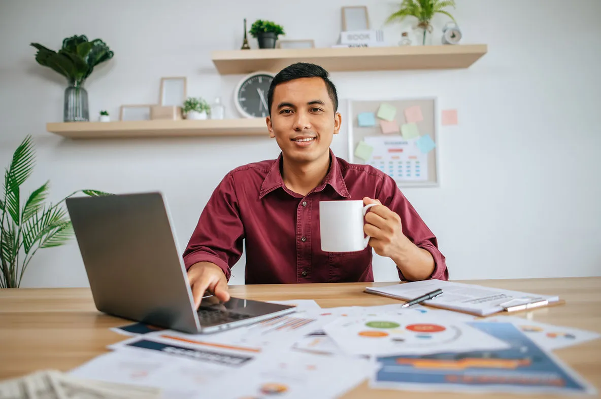 A Filipino freelancer looking relaxed in front of finance paperwork and a laptop
