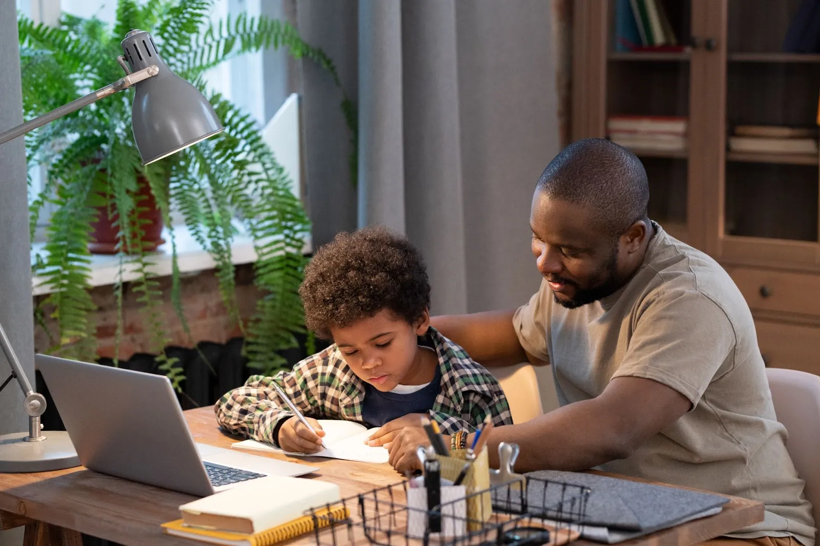 father-helping-son-with-homework-at-desk-with-laptop-books-and-lamp-in-cozy-home-office-setting-edge-tutor