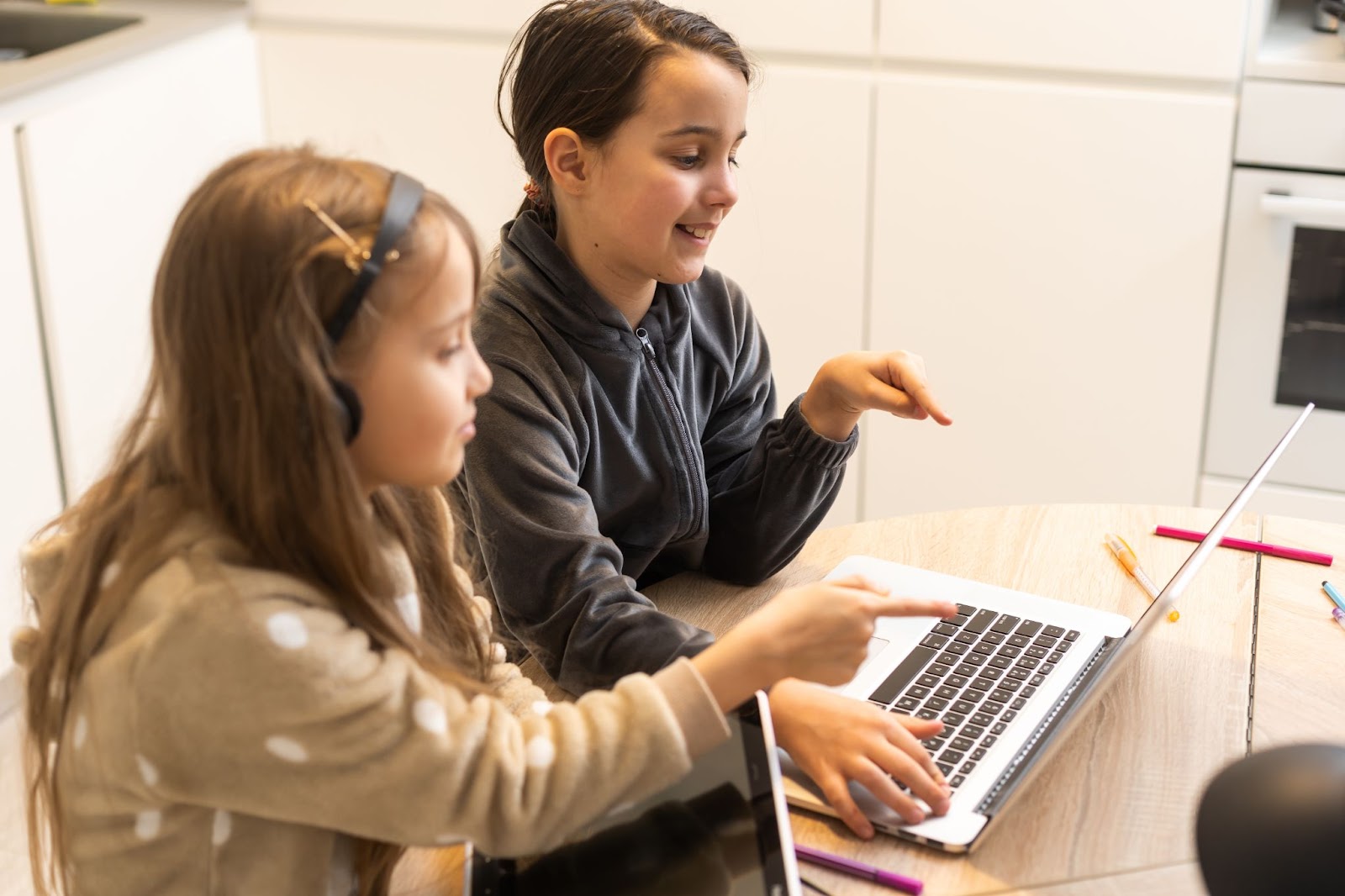 two-girls-learning-together-on-laptop-at-home-wearing-comfy-clothes-headphones-and-smiling-while-pointing-at-screen-during-online-study-session-edge-tutor