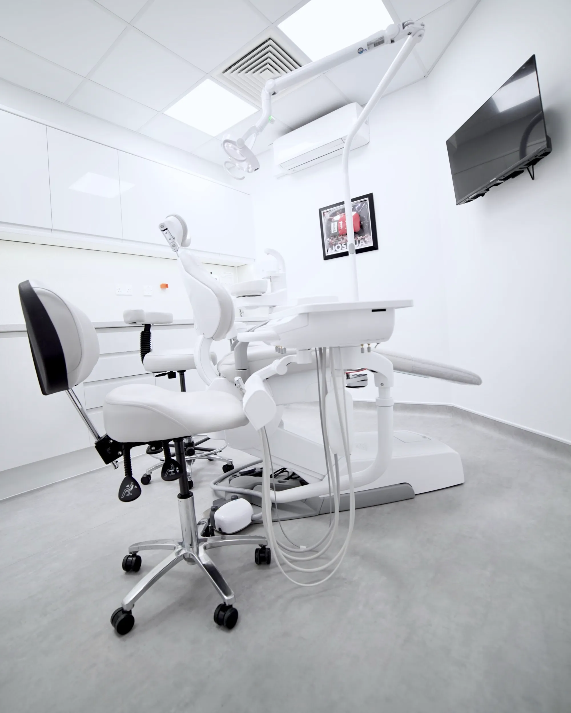 Modern white dental exam room with chair, equipment, and overhead light