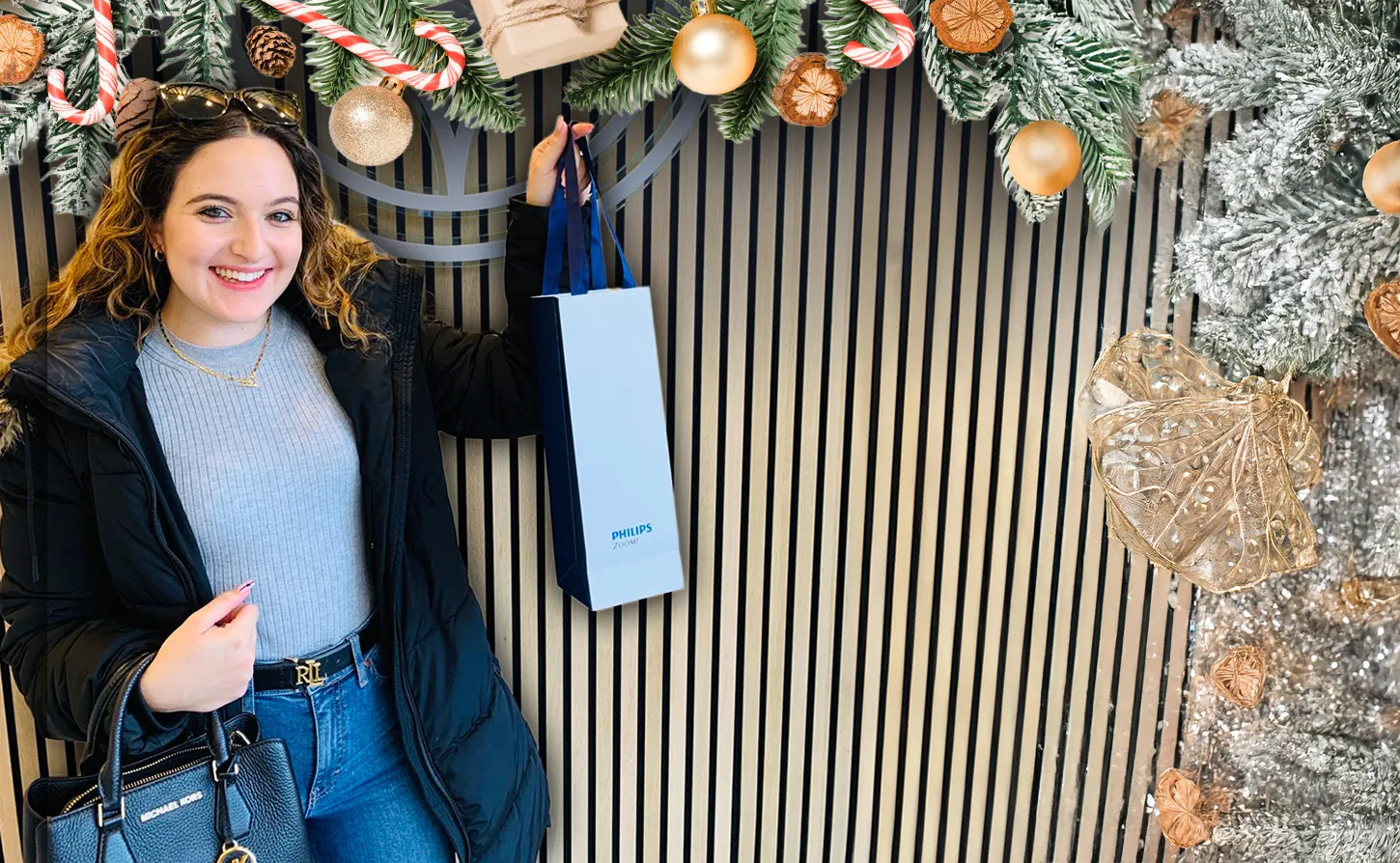 Smiling woman in winter coat holding a shopping bag with festive Christmas decorations around the image border.