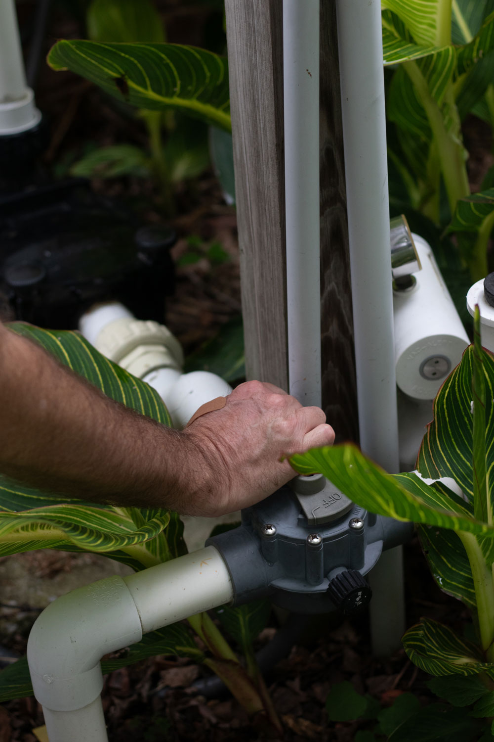 Close-up of a pool plumbing valve and adjoining PVC pipes during an equipment inspection