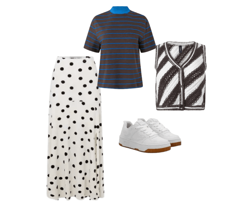 camiseta listrada azul e marrom, colete listrado preto e branco, saia longa branca de bolinhas, tênis branco.