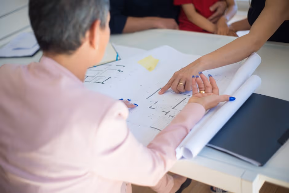 Business partners reviewing blueprints and shaking hands - commercial construction bridge loans