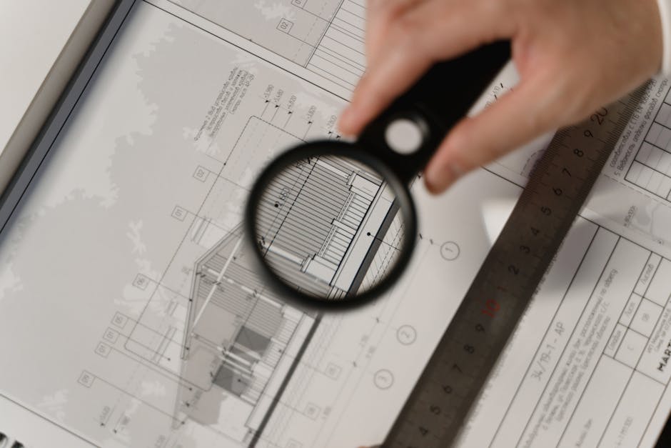 blueprint with magnifying glass over budget - Construction completion financing