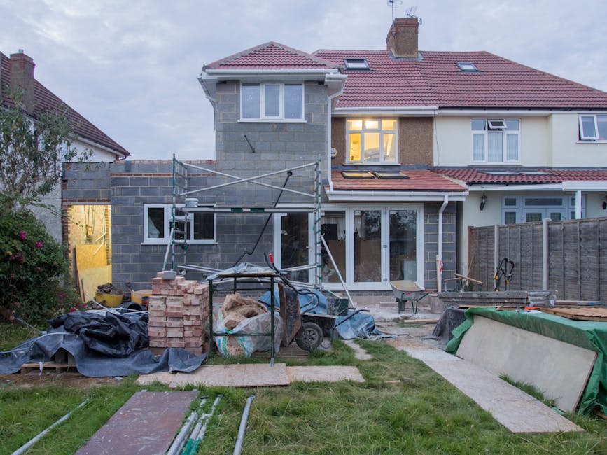 Image of a house being renovated with scaffolding and construction materials around it - hard money loan
