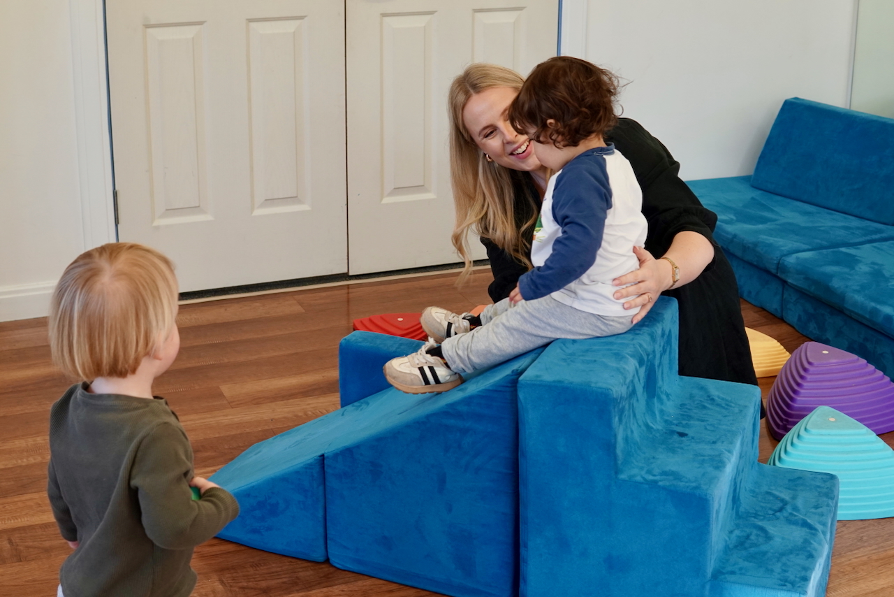 A therapist playing with children on blocks