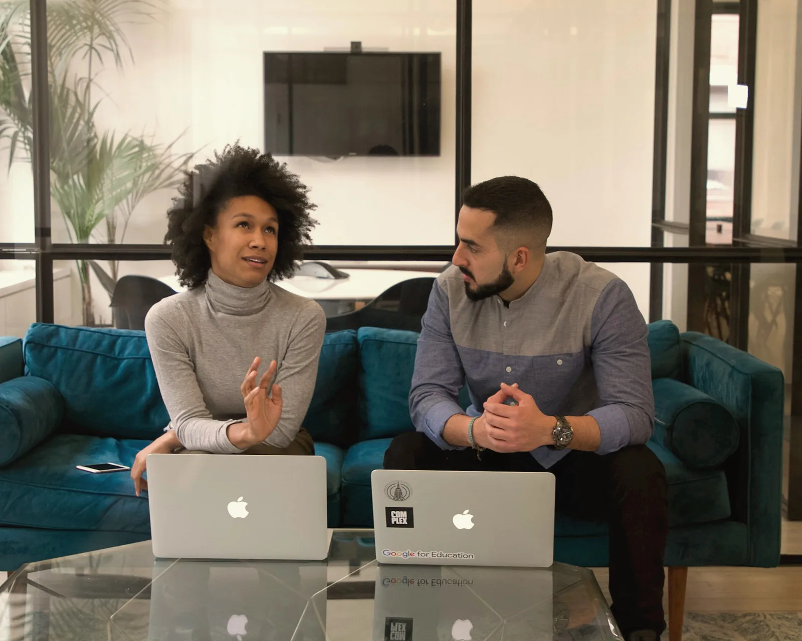 A man and a woman sitting in front of laptops