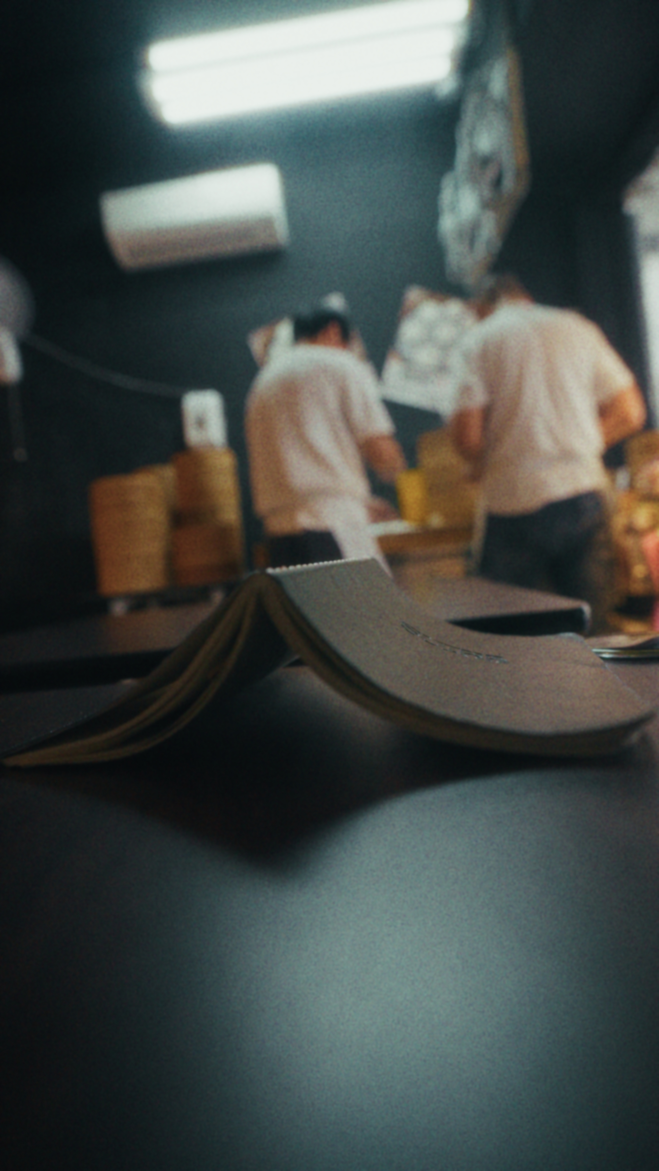 The notebook open on a counter while cooks work behind it at a dumpling shop