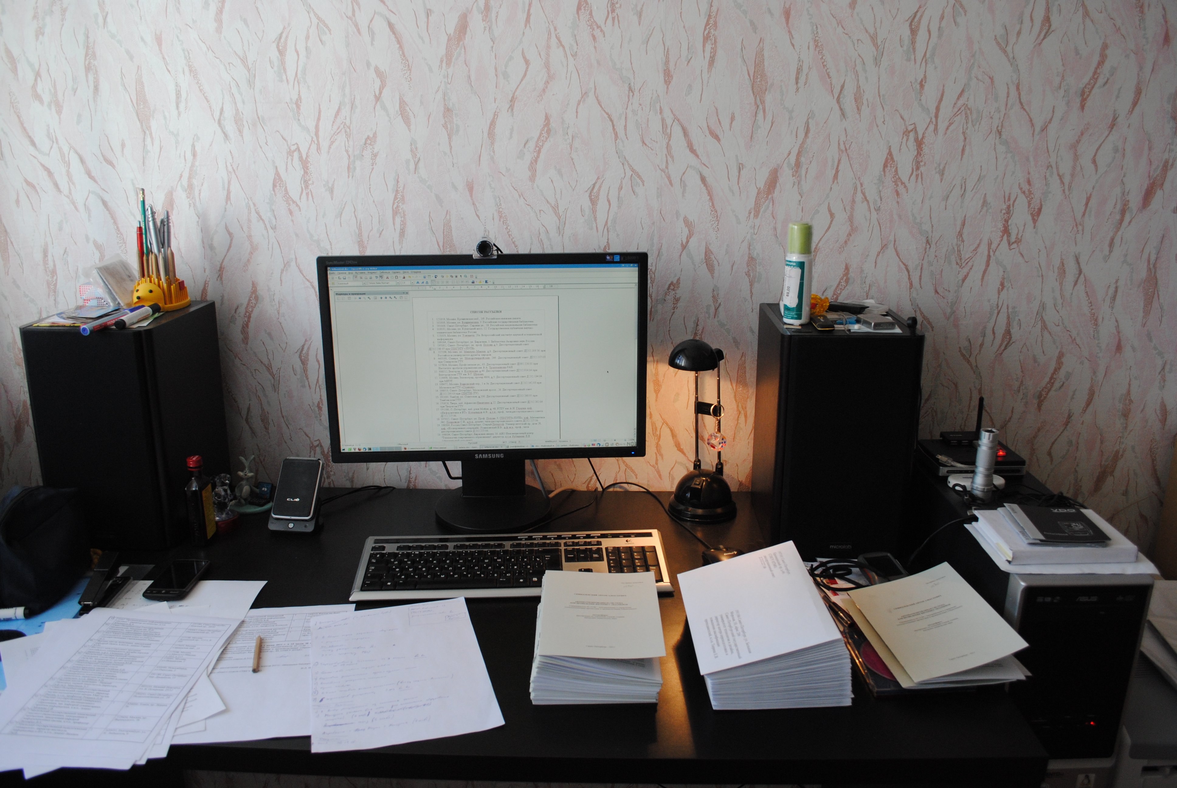 Computer desk is filled with printouts, notes, and booklets, with his PC displaying a reference list for his PhD thesis, hours before its defense