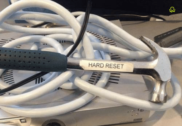 An image of hammer labeled as "hard reset," resting on top of tech.