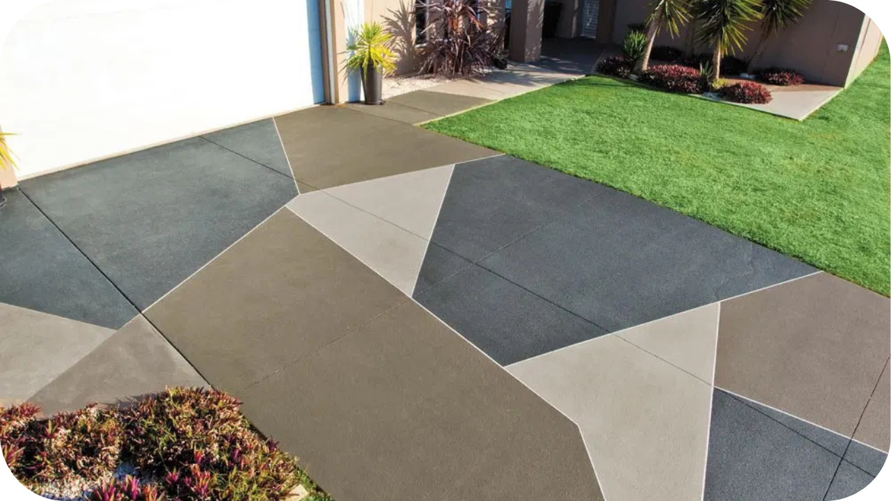 A modern concrete driveway with a large, abstract geometric pattern made of different colored and shaped sections of concrete.