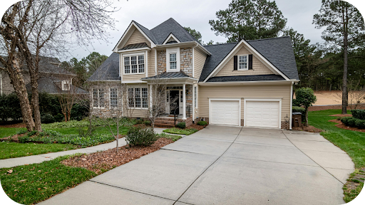 Modern suburban home with a neat concrete driveway Melbourne residents value, framed by landscaped gardens, leading to a double garage and stylish two-storey facade.