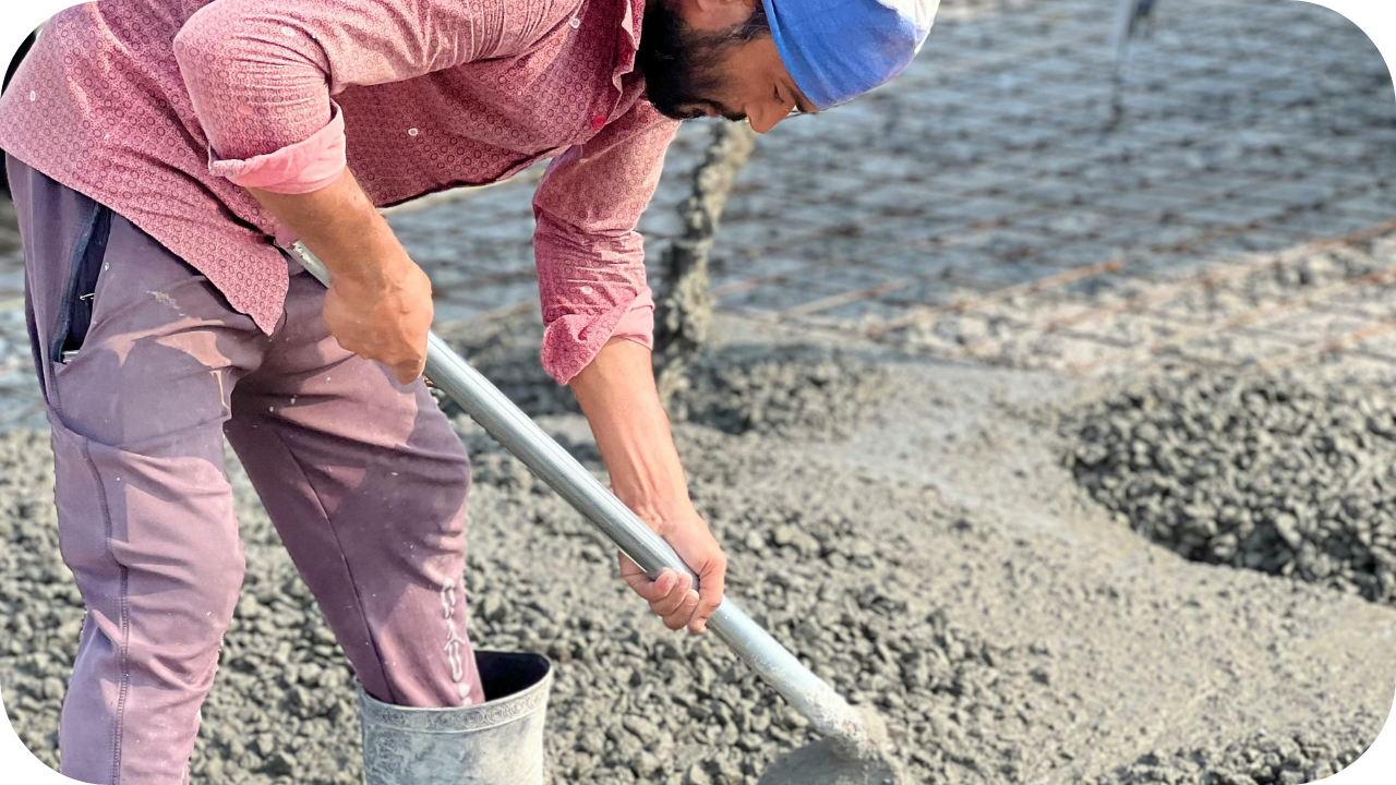 Worker spreading wet concrete with a shovel over steel reinforcement, showing the strength and durability of concrete driveways Melbourne homeowners rely on.