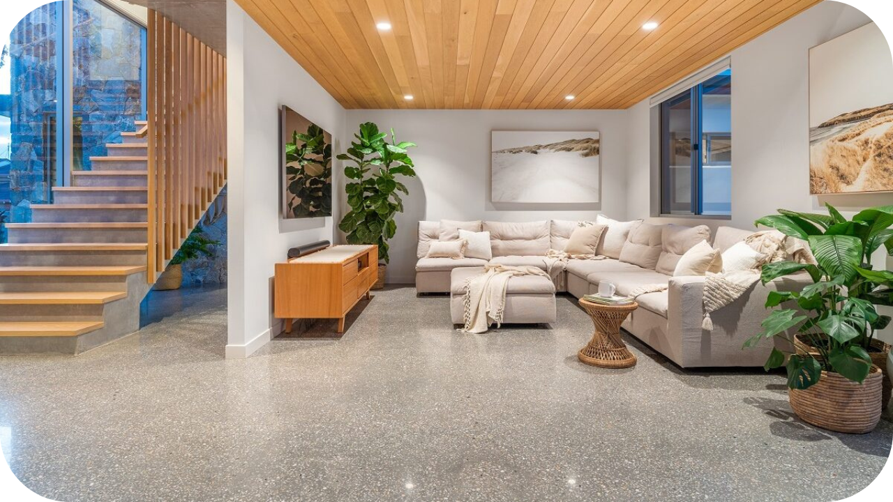Stylish living room with polished concrete floors, timber ceiling, modern furniture, and indoor plants.