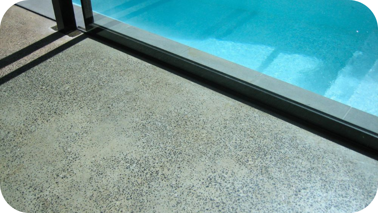 Polished concrete poolside flooring beside clear blue water, offering durability and slip resistance.